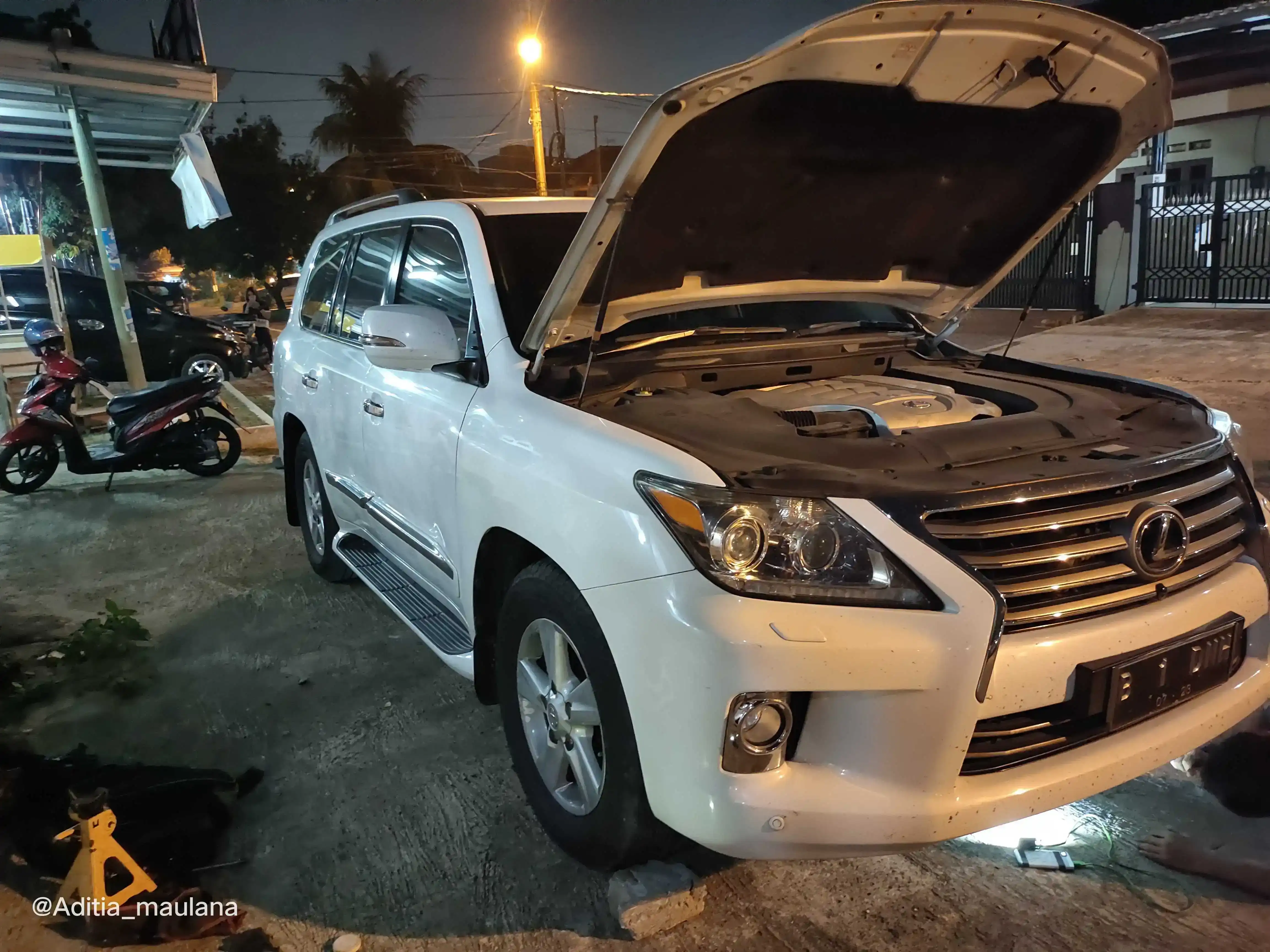 Teknisi Kuningan Motor sedang memperbaiki mesin mobil mogok di lokasi jalan
